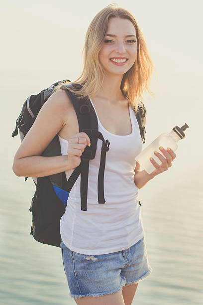 istock Smiling backpacker girl is holding water bottle 485112054