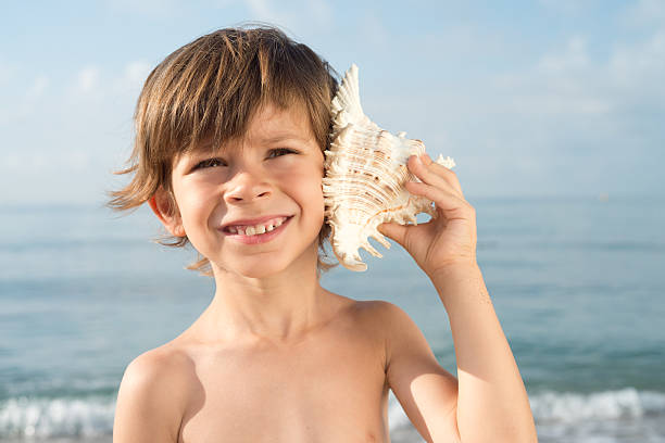 istock child listening conch looking up 485113134