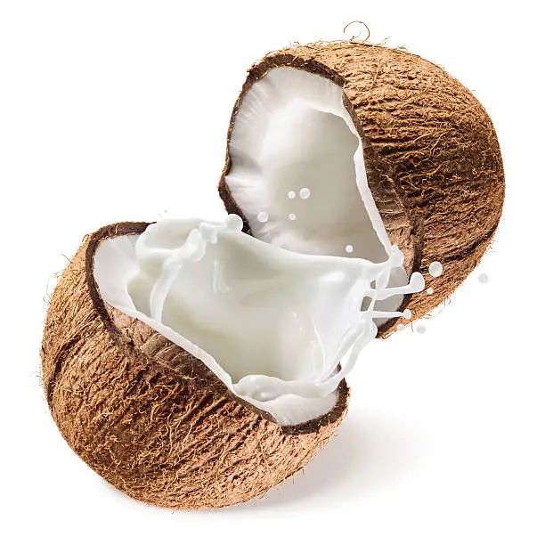 Photo of Coconut and a half with milk splash on white background