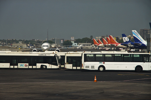 Mumbai, MH, India - April 26, 2015: A view of Mumbai Civil Airport which is one of the busiest in India. In the picture seven carriers are paked and two aircrafts are taxing. In the foreground are the busses that ferry passengers to the terminals. This is very symbolic to the pace of growing economy of India.