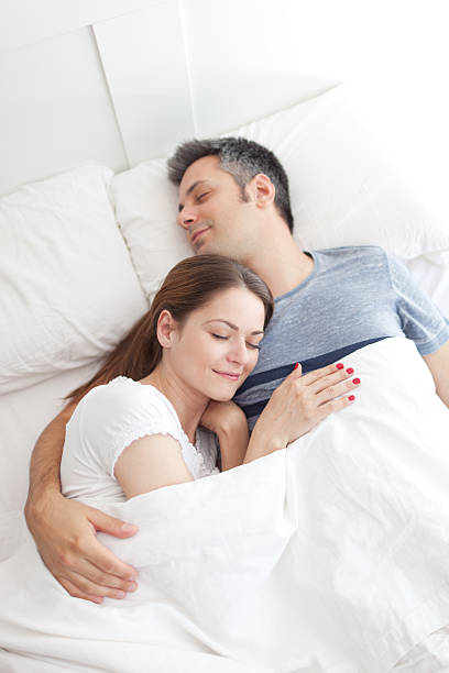 coppia di dormire nel letto - couple affectionate relaxation high angle view foto e immagini stock