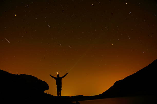 istock silhouette man arms raised into stars sky 485124016