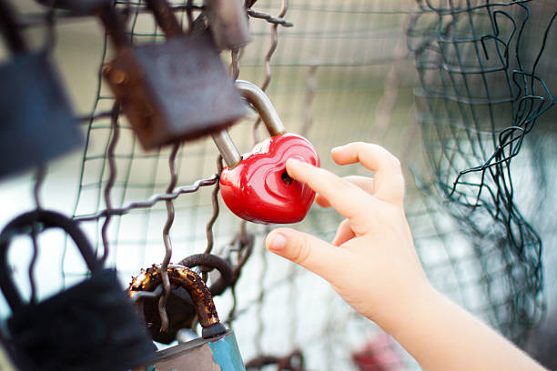 istock Child's hand touching a padlock clipped to a wire mesh 485136282