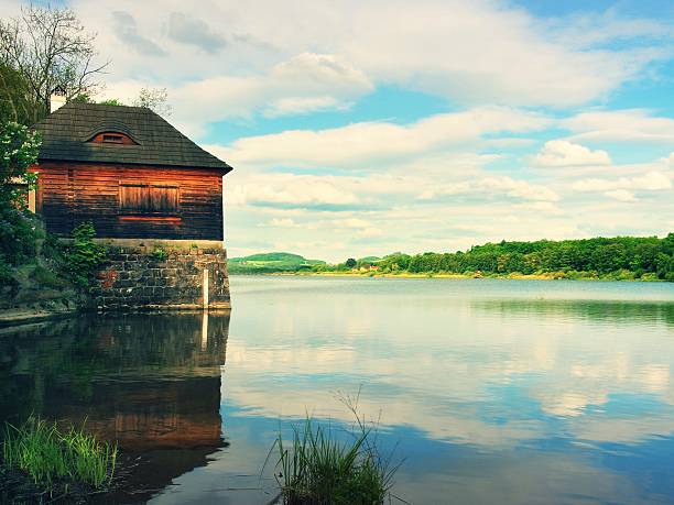 lago di mattina con vecchio stile da pesca in legno hut sulla banca - underpinning foto e immagini stock