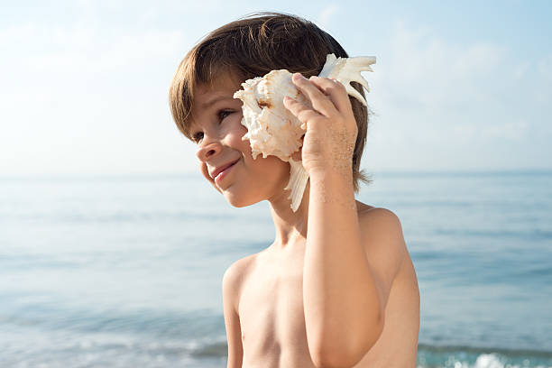 istock child listening conch looking sideways 485146226