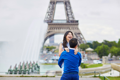 Young romantic Asian couple on Trocadero view point near the Eiffel tower in Paris, France