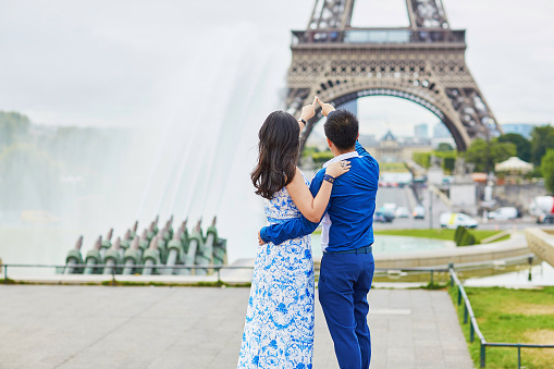 Young romantic Asian couple on Trocadero view point near the Eiffel tower in Paris, France