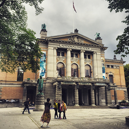 Oslo, Norway  - July 18, 2015: Asian tourists photographing in front of Oslo National Theatre
