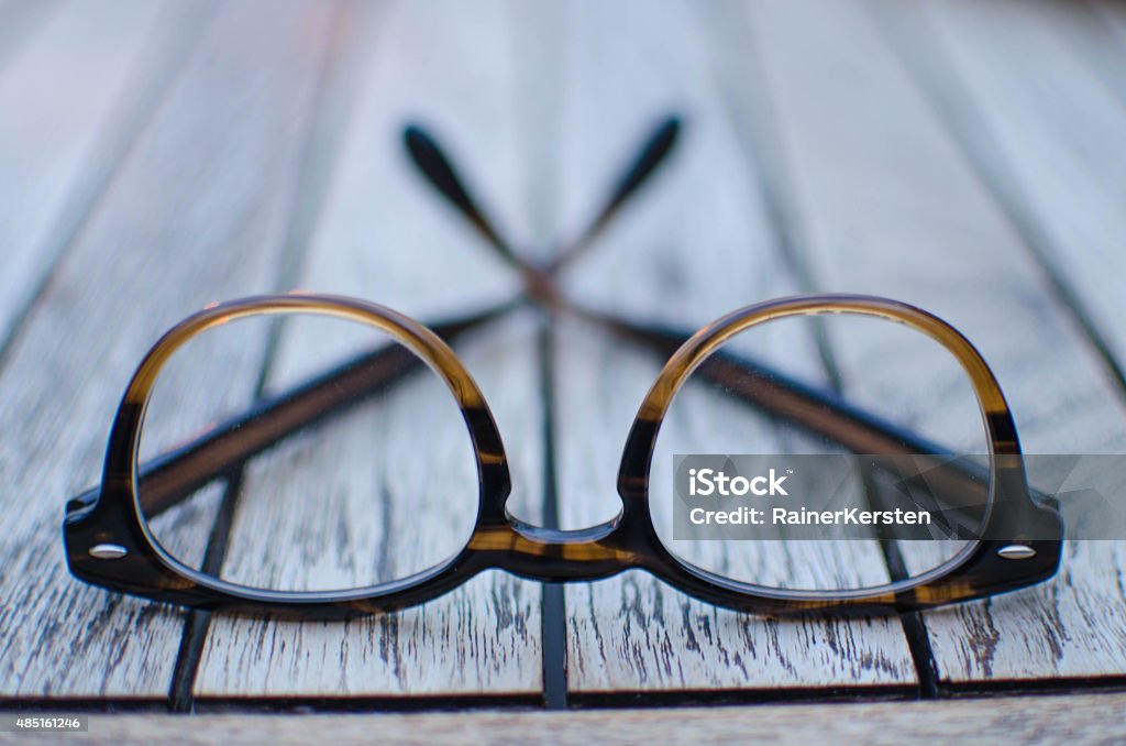 Pair of glasses on a wooden table A pair of brown glasses lying on a wooden table. Eyeglasses Stock Photo