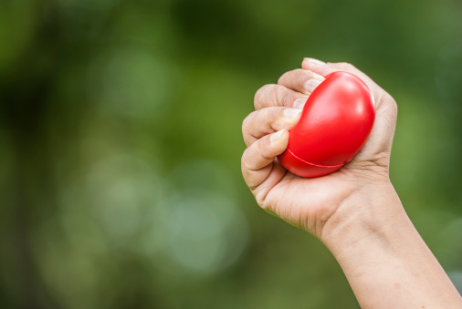 Hand squeezing a stress ball isolated on natural bokeh background