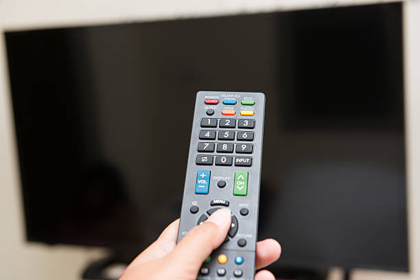 istock hand pressing remote control to turn on the TV 485165342