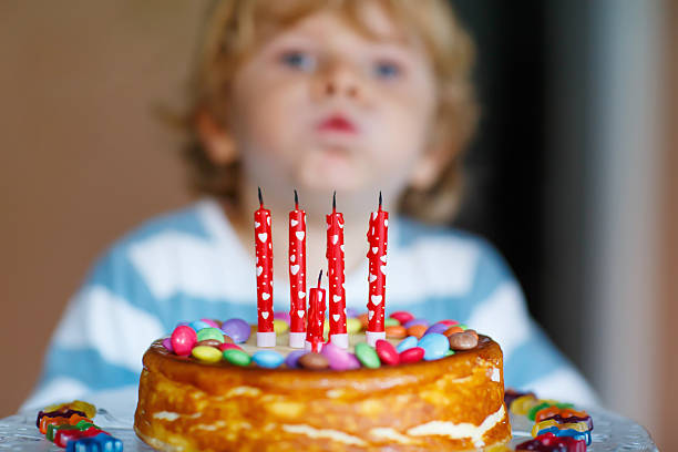 istock kid boy celebrating his birthday and blowing candles on cake 485165580