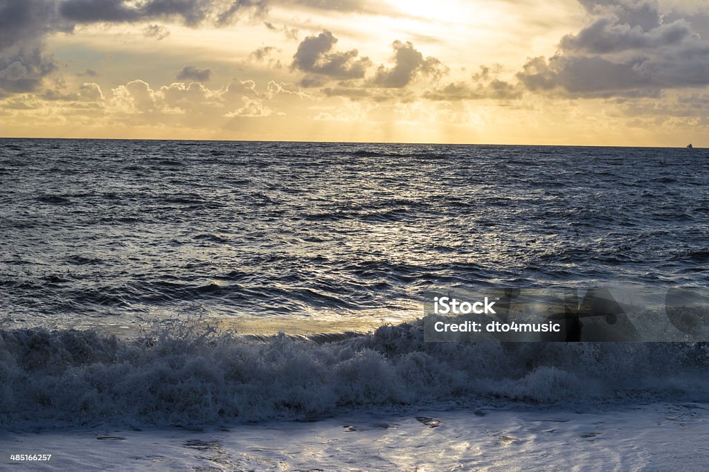 Sun rays through cloud on Hove beach The sun is setting on Hove seafront and the sun rays are shining through the clouds Beach Stock Photo