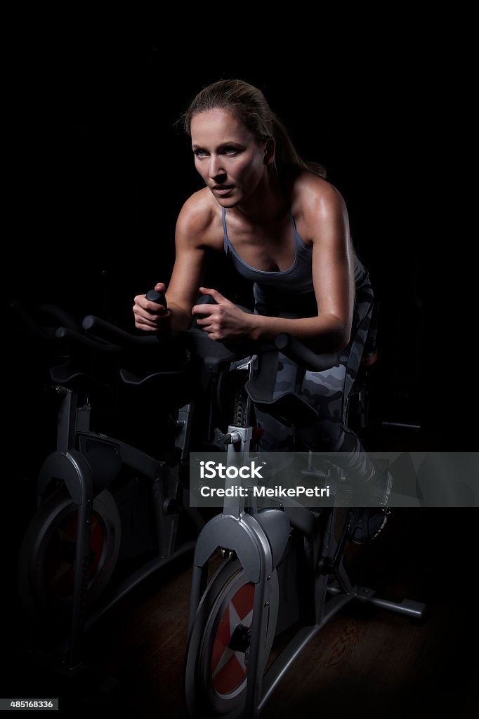 Female Athlete Cycling in Gym Young and attractive woman is cycling in the gym. Health Club Stock Photo