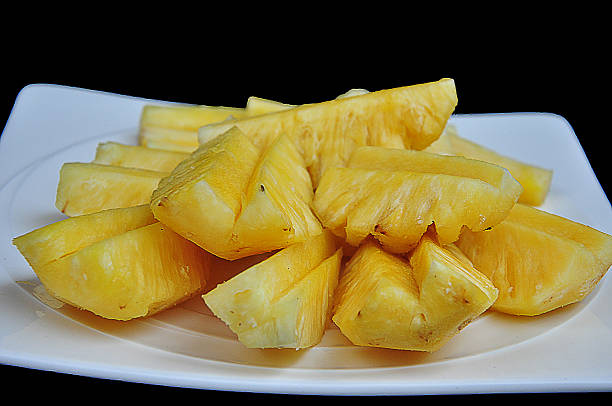 istock White dish of peeled pineapple on black background 485172054