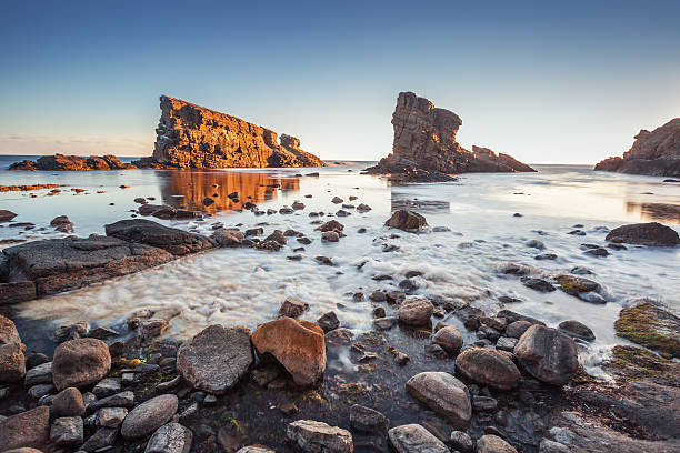 istock Dramatic sunrise with mist on the beach with rocks 485175884