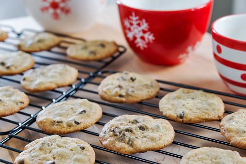 Freshly baked hot chocolate chip cookies are cooling on baking racks for the Christmas holidays.  Fresh baked desserts are a staple of the Christmas holidays around the world.