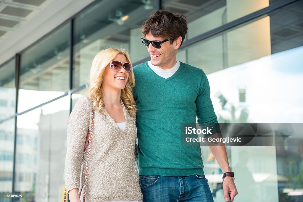 Couple in shopping Young satisfied couple walking in the city with shopping bags. Young satisfied couple sitting on the park bench and looking in the shopping bag.  Men Stock Photo