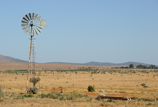 A wind-powered waterpump in the South Australian Outback near the town of Hawker, farm in the distance