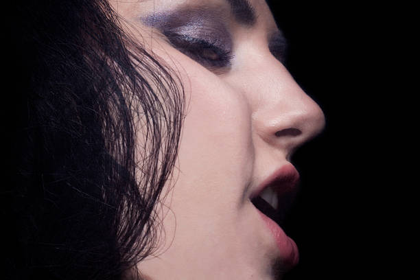 Young blondhaired woman singing against black background