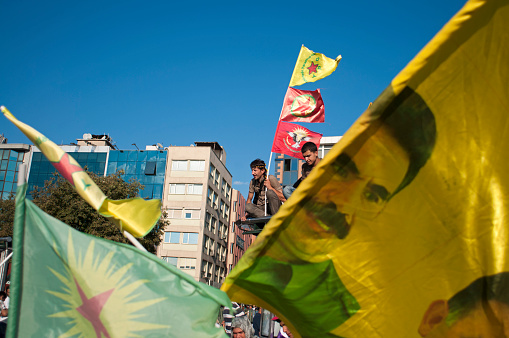 Istanbul, Turkey -September 01, 2013: The teenager is showing flags of YPG on the first plan posters of Abdullah Ocalan, the leader of PKK, during the world peace day demonstration in Kadikoy, Asian part of Istanbul, Turkey. PKK stands for Kurdistan Workers Party and it carries out independence movement against Turkish State. This includes also armed struggle. Abdullah Ocalan is the indisputable leader of this movement.