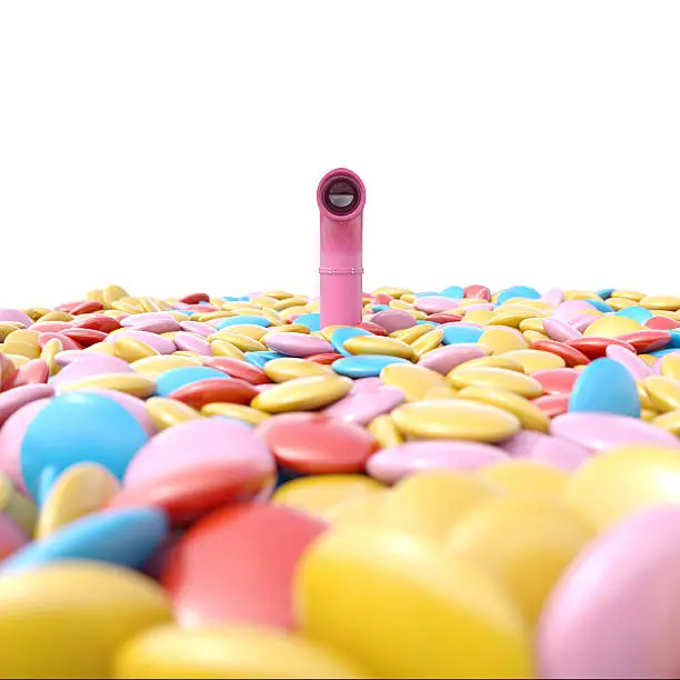 Periscope above sea of candies over white isolated background