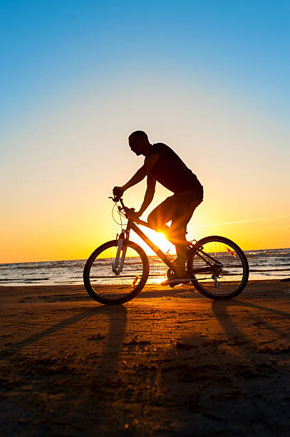 istock Man cyclist silhouette on blue sky and multicolored sunset background. 485209670