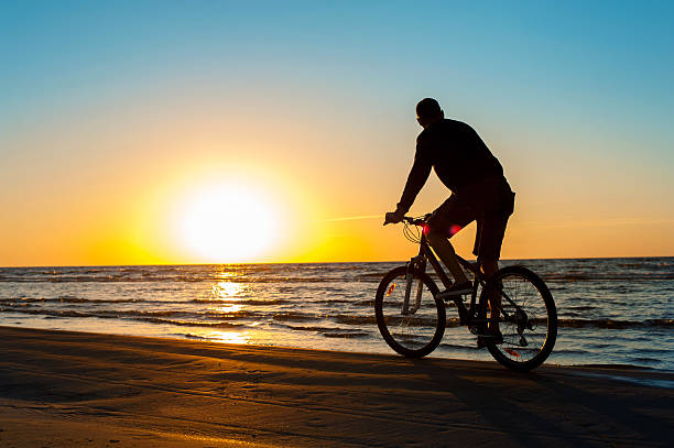 istock Man cyclist silhouette on blue sky and multicolored sunset background. 485209676