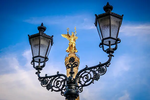 The Victory Column (Siegessäule), is a well known, 67 meters high monument in Berlin, Germany. The bronze sculpture of Victoria on top of the column, 8.3 metres in height, has the nickname "Goldelse". A street lantern in the foreground framing the monument.