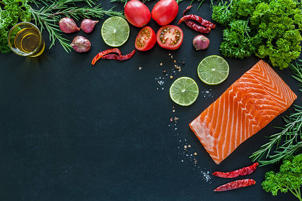 istock Salmon fillet with garnish on blackboard ready to cook 485245138