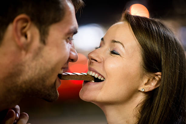 Couple eating chocolate on date stock photo