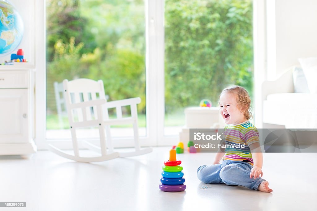 Happy laughing toddler girl playing in room with big window Happy laughing toddler girl playing in a white room with a big window with garden view Child Stock Photo