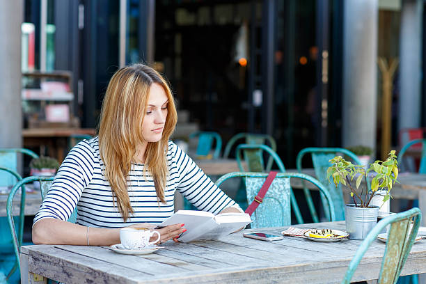 istock Woman drinking coffee and reading book in cafe 485261732