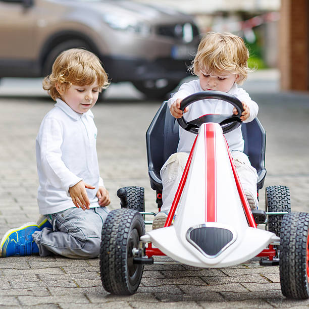 dos hermanos felices niños jugando con coche de juguete - car child teamwork sports race fotografías e imágenes de stock
