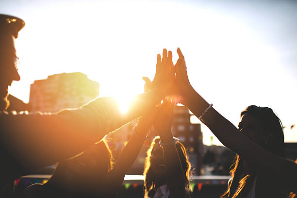 Happy friends at the rooftop doing high five Happy friends celebrating the success with high five Unity stock pictures, royalty-free photos & images