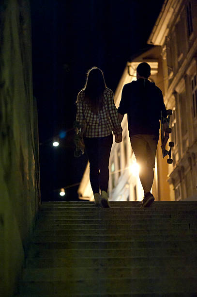 Alegre Pareja Caminando Con Monopatín Al Aire Libre Foto de stock y más banco de imágenes de Noche - iStock Alegre Pareja Caminando Con Monopatín Al Aire Libre Foto de stock y más banco de imágenes de Noche - iStock