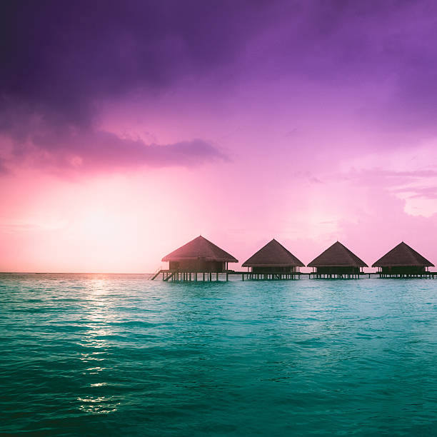 Beach in Maldives at sunset, wooden jetty and small shed. Exotic holiday destination