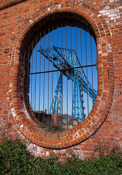 Middlesbrough Transporter bridge framed by an oval brick wall Built in 1911 the listed building Middlesbrough Transporter bridge which traverses over the river Tees in North-east England framed by an oval brick wall. middlesbrough stock pictures, royalty-free photos & images