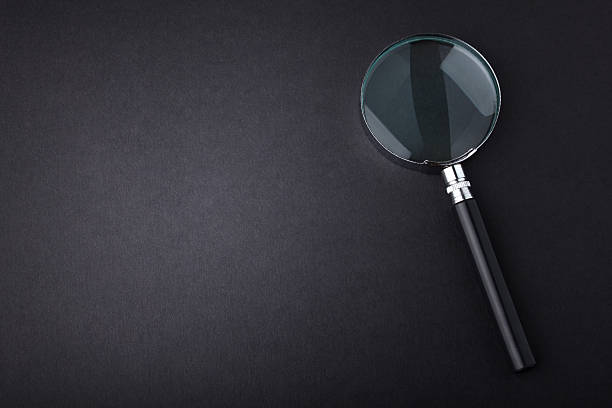 istock Closeup of magnifying glass on dark surface 485292427