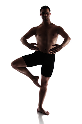 Silhouette of an muscular adult male modern contemporary ballet style dancer. Dancer is wearing black ski pants and is isolated on a white background.