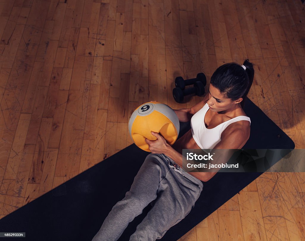 Strong young woman doing core workout Top view of strong young woman doing core workout using kettlebell weight. Muscular female exercising on fitness mat in gym. 20-29 Years Stock Photo