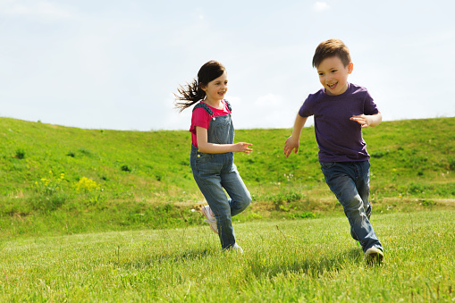 A small group of children are seen running a Cross Country race in a small pack together. They are each wearing comfortable athletic wear and are focused on the path as they run towards the finish line.