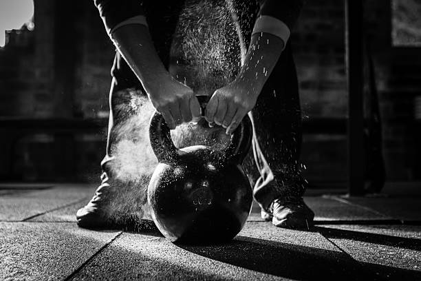 gym Kettle Bell with chalk and hands A gym kettle bell is best used with chalked up hands to prevent slipping as you work hard and sweat hard. kettlebell stock pictures, royalty-free photos & images