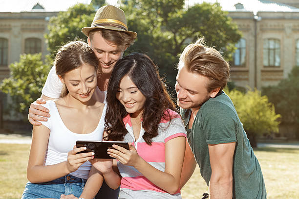 istock Happy young people sitting on the grass and smiling 485305660