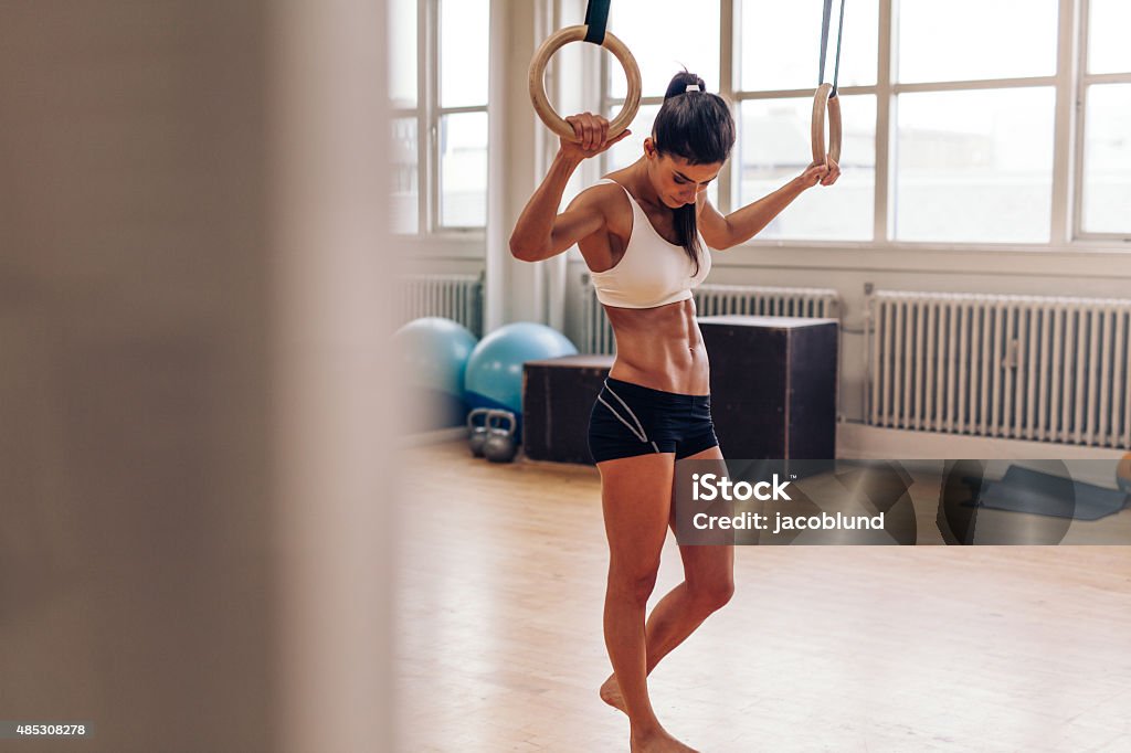 Woman exercising with gymnastic rings in gym – Jacob Lund