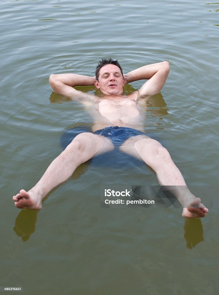 Enjoying vacation Man floating on the tire in the lake.  Lake Stock Photo