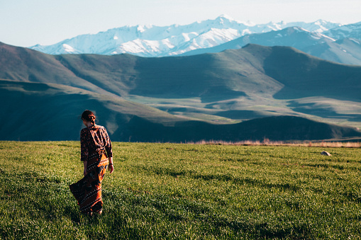 Girl in the field on the background of mountains 