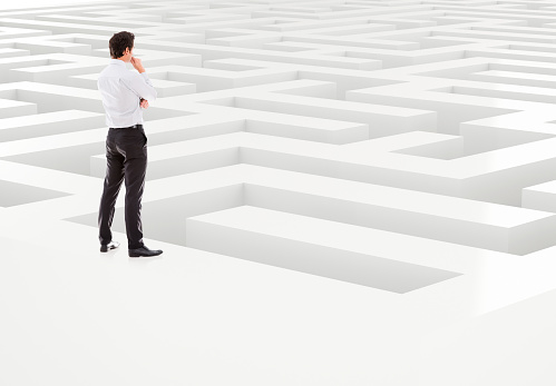 Business man trapped in a 3D  maze thinking on a way out - isolated