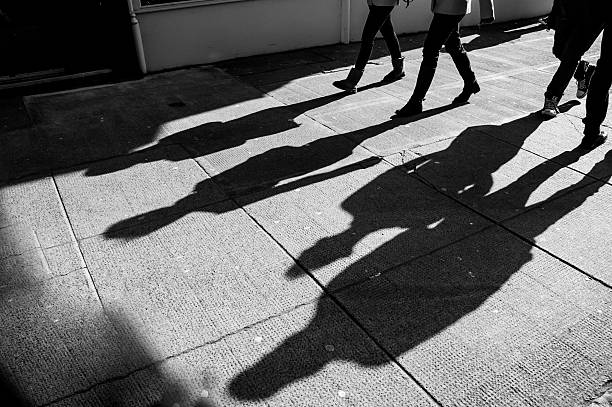 istock Shadows of four walking pedestrians projected on the sidewalk 485316689
