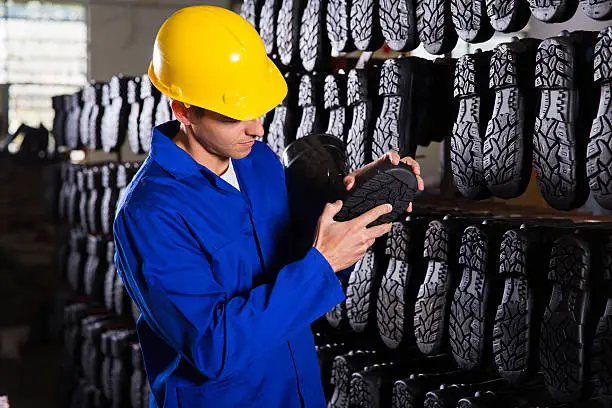 quality controller checking rubber-boots sole in storeroom